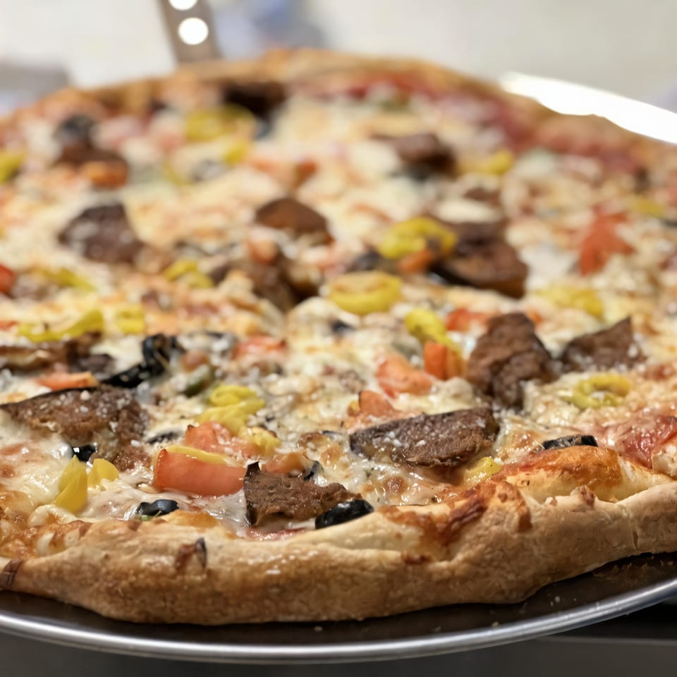 A Medo's Italian Restaurant pizza, topped with cheese, olives, tomatoes, peppers, and sausage.